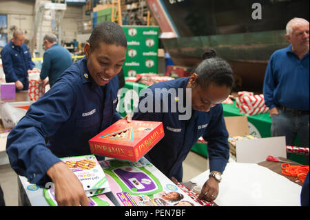 Coast Guard members and Isaiah Thomas of the Boston Celtics wrap holiday gifts for the children of military families at Coast Guard Base Boston, Thursday, Dec. 17, 2015.  The event was a joint effort between World Vision, the Boston Celtics, and the U.S. Coast Guard. (U.S. Coast Guard photo by Petty Officer 3rd Class Andrew Barresi) Stock Photo