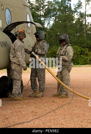 From right, U.S. Army Sgts. David Pressnell and David Uplinger 1-228th Aviation Regiment flight engineers and Spc. Tyree Doyle, Joint Task Force-Bravo Petroleum, Oil and Lubricant specialist refuel a U.S. Army CH-47 Chinook Dec. 17, 2015 at Mocoron Airfield in the Gracias a Dios Department (state) of Honduras. The airfield provides the flying forces a hub to refuel at and embark from when conducting CARAVANA troop movements in the area. The troop movements are part of a combined U.S. and Honduran effort to disrupt the flow of illicit drugs and materials through the region. (U.S. Air Force phot Stock Photo