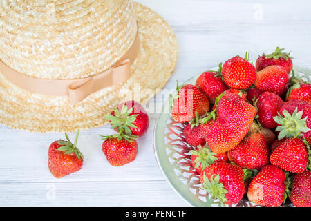 Strawberry and straw hat. Summer still life. Strawberries on a white wooden background Stock Photo