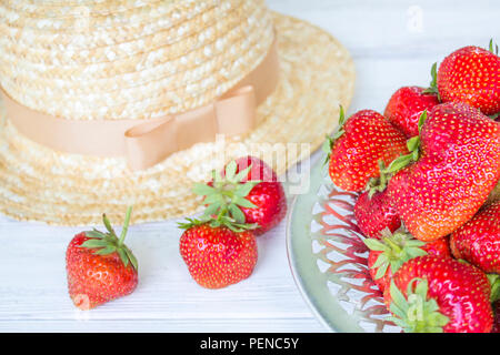 Strawberry and straw hat. Summer still life. Strawberries on a white wooden background Stock Photo