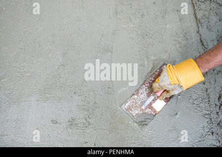 Construction worker - plastering and smoothing concrete wall with Stock