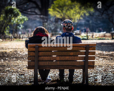 Park Life Tokyo Yoyogi Park - a couple relax on a park bench in Yoyogi Park in Shibuya-ku Tokyo Japan Stock Photo