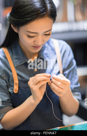 Young leather craftswoman working in studio Stock Photo