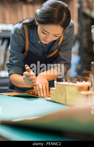 Young leather craftswoman working in studio Stock Photo