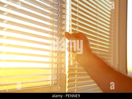 Man's hand opens the horizontal blinds on the Windows. Stock Photo
