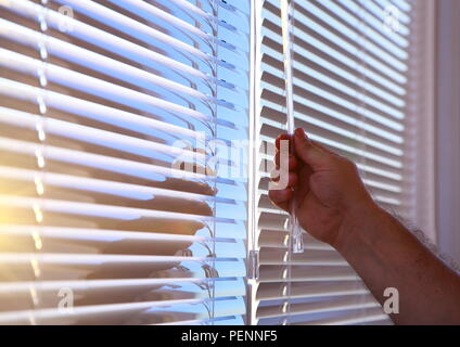 Man's hand closes the horizontal blinds on the Windows. Stock Photo