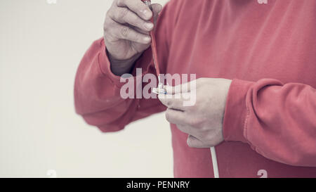 Retro toned image of electrician affixing a connector to an electric cable with a screwdriver in a close up view of his hands. Stock Photo