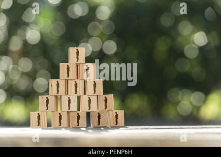 Pyramid of toy wooden blocks with human icons of a businessman conceptual of management structure, human resources, business hierarchy, teamwork and e Stock Photo