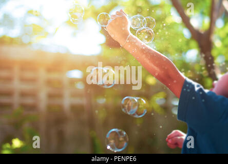 Blurred concept young children playing with bubble toy in the garden with sunlight. Stock Photo