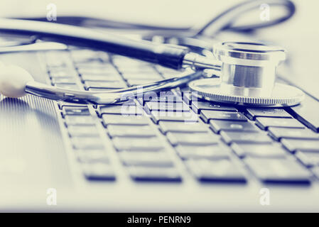 Retro effect faded and toned image of a medical stethoscope on computer keyboard. Concept of computer support. Stock Photo