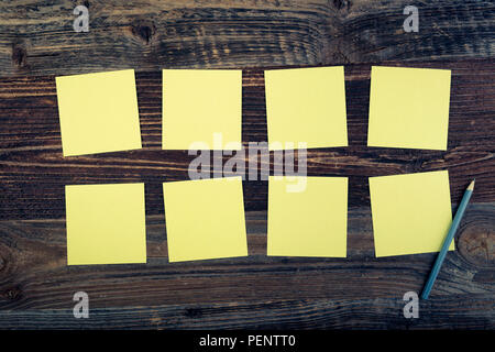 Bunch of yellow sticky notes on the wooden background. Stock Photo