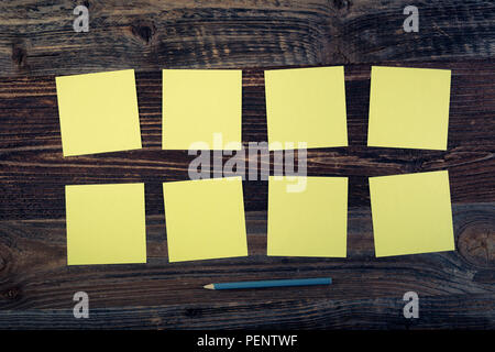 Bunch of yellow sticky notes on the wooden background. Stock Photo