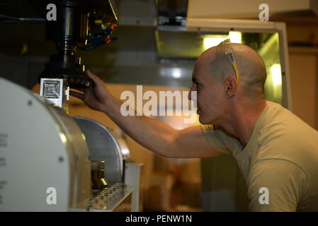 A Staff Sergeant from the 28th Maintenance Squadron inspects a Haas VF-6 machine at Ellsworth Air Force Base, South Dakota, before cutting a metal block. The machine is programmed using a 3-D model computer system to produce precise aircraft components. The metals flight manufactures parts not available through standard supply channels, supporting the 28th Bomb Wing and Air Force Global Strike Command, highlighting the role of skilled technicians in aircraft maintenance, fabrication, and mission readiness. Stock Photo