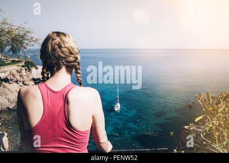 rear view of young woman in sportswear looking at sea Stock Photo