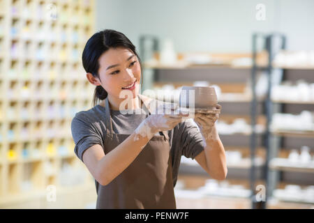 Young potter examining pot in studio Stock Photo