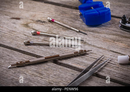 Set of watchmaker tools isolated on a rough wooden board close up Stock Photo