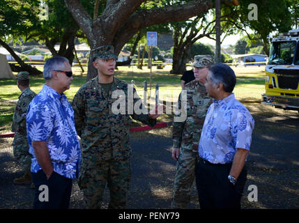 Maj. Eric Min, operations Marine Aircraft Group 24, Marine Corps Base Kaneohe Bay, Hawaii, explains the setup outside the Haleiwa Incident Command Post, to Maj. Gen. Arthur 'Joe' Logan, adjutant general, Hawaii, and David Y. Ige, governor of Hawaii, during a visit to the ICP, Jan. 18, 2016. Logan and Ige both visited the ICP to give thanks to all those involved in the search for 12 missing Marines who were involved in a helicopter crash off the North Shore of Oahu. (U.S. Coast Guard photo by Petty Officer 1st Class Levi Read/Released) Stock Photo
