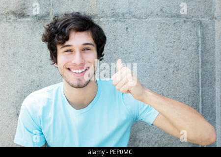 Caucasian young adult man with blue eyes showing thumb up outdoors with copy space Stock Photo