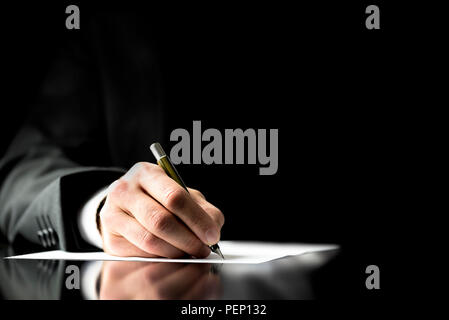 Businessman signing a document, taking notes, completing a questionnaire or writing correspondence, close up view of his hand and the paper Stock Photo