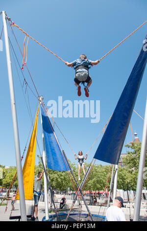 Kids enjoying bungee trampoline jumping in Ouchy park in Lausanne, Switzerland on sunny summer day Stock Photo