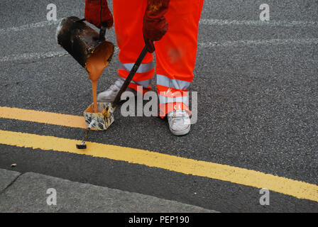 Worker painting double yellow line on the road Stock Photo