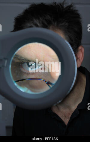 Closeup of eye seen through magnifying loupe Stock Photo