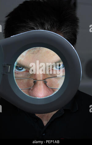 Closeup of eye seen through magnifying loupe Stock Photo