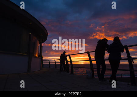 Aberystwyth Wales UK, Thursday 16 August 2018  UK Weather: People silhouetted leaning on the seaside railings watching the sunset over the sea in Aberystwyth Wales.  photo © Keith Morris / Alamy Live News Stock Photo