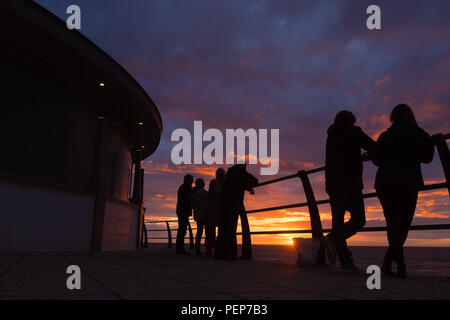 Aberystwyth Wales UK, Thursday 16 August 2018  UK Weather: People silhouetted leaning on the seaside railings watching the sunset over the sea in Aberystwyth Wales.  photo © Keith Morris / Alamy Live News Stock Photo