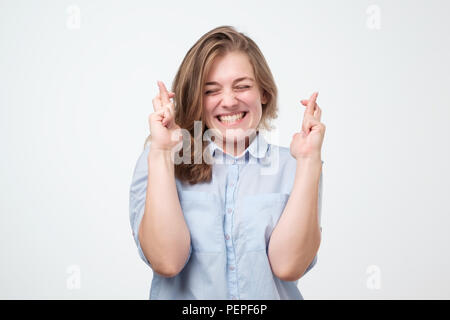 Lucky beautiful european female crosses fingers , hopes all wishes come true. People, body language and happiness concept Stock Photo