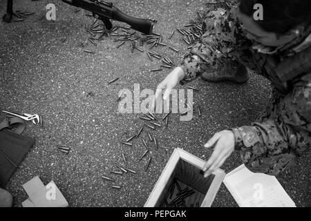 A sailor collects empty shell casings during a weapons sustainment ...