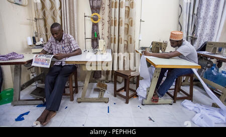 Stone Town, Zanzibar, 13 January - 2015: Tailoring shop with young man sowing and old man reading. Stock Photo