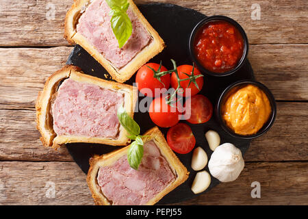 Meat terrine, pate with spices, garlic served with vegetables and sauces close-up on the table. Horizontal top view from above Stock Photo