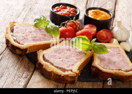 Delicious French brioche stuffed with a pork terrine with vegetables and sauces close-up on the table. horizontal Stock Photo