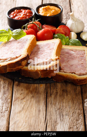 French food: terrine, pate in a brioche with spices, garlic served with vegetables and sauces close-up on the table. vertical Stock Photo