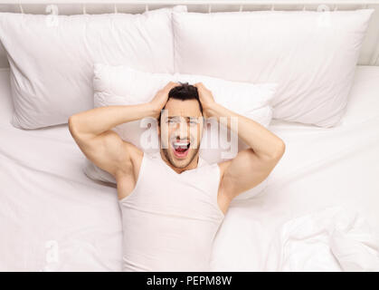 Frustrated young man lying in bed Stock Photo