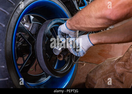Side view portrait of man working in garage repairing motorcycle. Hands close up Stock Photo