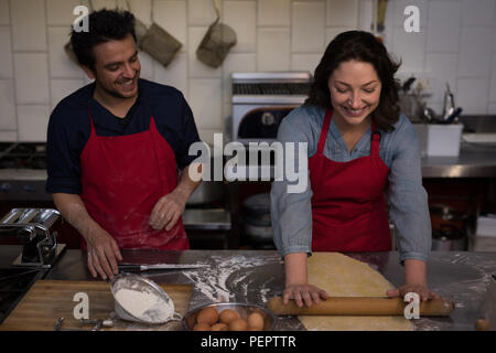 Female Baker rolling a dough for making pasta Stock Photo