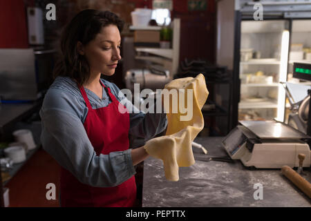 Female baker holding a pasta in hand Stock Photo