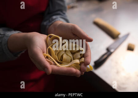 Tagliatelle in hand while baker making tagliatelle Stock Photo