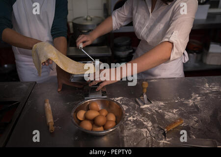 Bakers using machine for preparing pasta in bakery Stock Photo