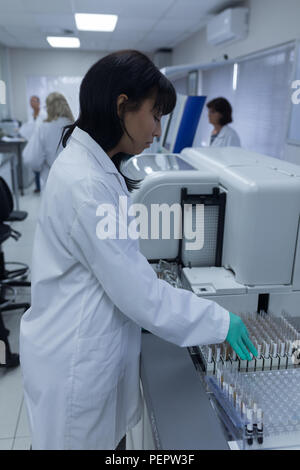 Mature nurse analyzing blood sample through machinery at laboratory ...