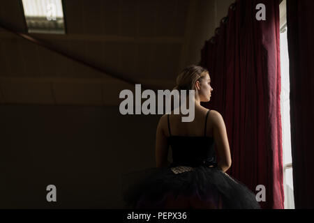 Thoughtful ballerina looking through window Stock Photo