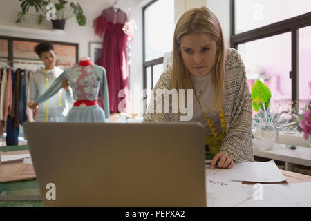 Fashion designer using laptop in fashion studio Stock Photo