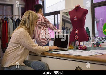 Fashion designer using laptop in fashion studio Stock Photo