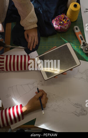 Fashion designers drawing a sketch using digital tablet in fashion studio Stock Photo