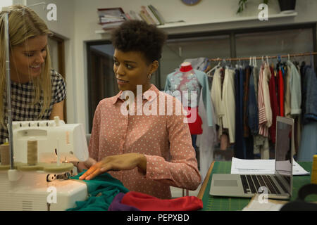 Fashion designers interacting while using sewing machine Stock Photo