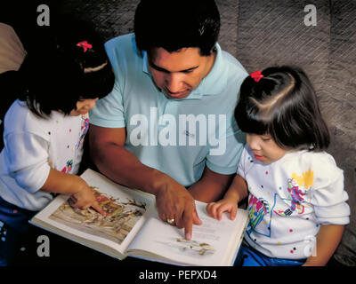 Mexican heritage dad reading storybook together with twin daughters sisters.  MR   © Myrleen Pearson  ...Ferguson Cate Stock Photo