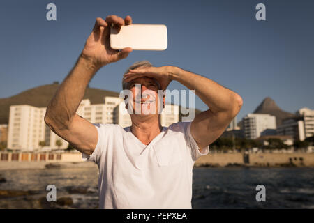 Senior man taking selfie near sea side Stock Photo