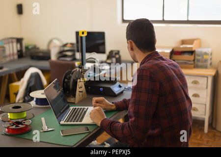 Mechanic using laptop on table in workshop Stock Photo